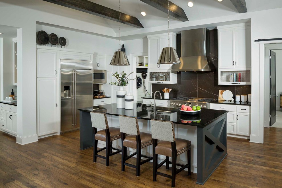 Photo of a classic kitchen in Charlotte with recessed-panel cabinets, white cabinets, black splashback, stainless steel appliances, dark hardwood flooring, an island, brown floors and black worktops.