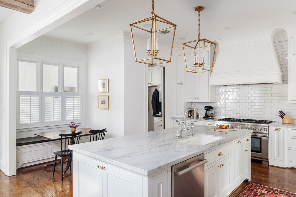 Inspiration for a timeless l-shaped medium tone wood floor eat-in kitchen remodel in Houston with an undermount sink, beaded inset cabinets, white cabinets, marble countertops, white backsplash, subway tile backsplash, stainless steel appliances and an island