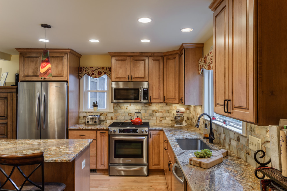 Mid-sized elegant l-shaped light wood floor eat-in kitchen photo in DC Metro with an undermount sink, raised-panel cabinets, medium tone wood cabinets, granite countertops, multicolored backsplash, ceramic backsplash, stainless steel appliances and an island