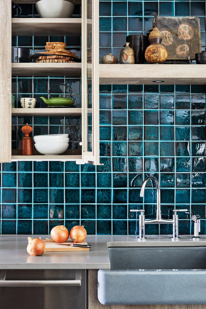 Imagen de cocina urbana de tamaño medio con puertas de armario marrones, salpicadero azul, electrodomésticos de acero inoxidable, una isla y encimeras grises