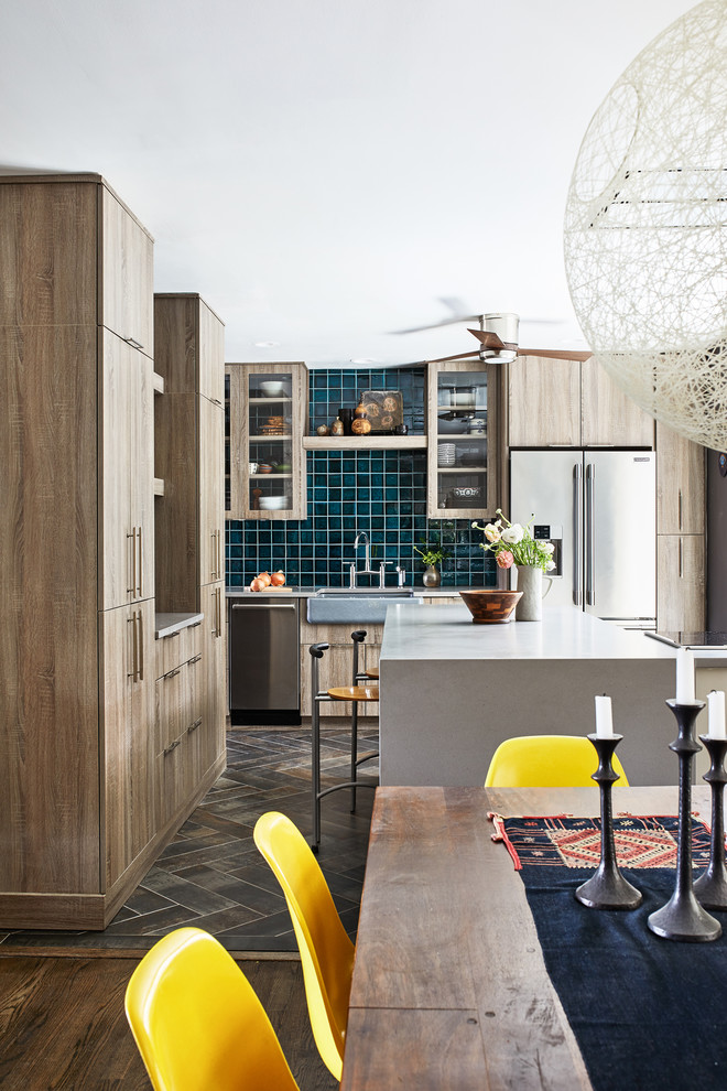Foto di un cucina con isola centrale industriale di medie dimensioni con ante marroni, paraspruzzi blu, elettrodomestici in acciaio inossidabile e top grigio