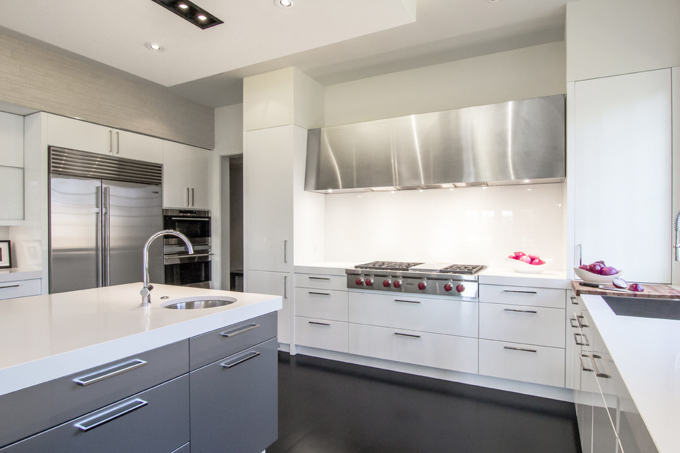 This is an example of a medium sized modern u-shaped kitchen/diner in DC Metro with a submerged sink, flat-panel cabinets, white cabinets, composite countertops, stainless steel appliances, dark hardwood flooring, an island, metallic splashback, mirror splashback and black floors.