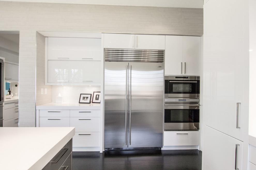 Inspiration for a mid-sized modern u-shaped dark wood floor and black floor eat-in kitchen remodel in DC Metro with an undermount sink, flat-panel cabinets, white cabinets, solid surface countertops, stainless steel appliances, an island, metallic backsplash and mirror backsplash