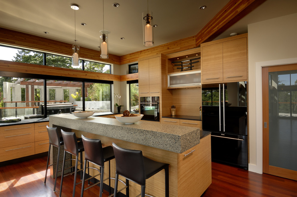 Inspiration for a contemporary l-shaped open plan kitchen in Vancouver with flat-panel cabinets, light wood cabinets, concrete worktops, window splashback, black appliances, dark hardwood flooring, an island and red floors.