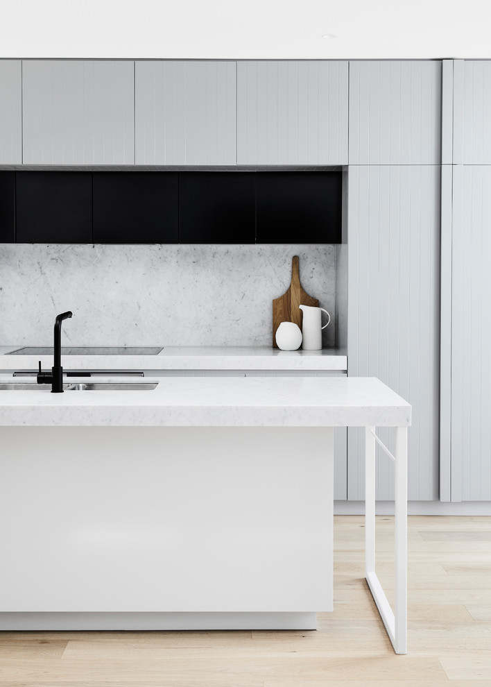 Photo of a medium sized contemporary galley open plan kitchen in Melbourne with a submerged sink, recessed-panel cabinets, grey cabinets, marble worktops, white splashback, marble splashback, stainless steel appliances, light hardwood flooring, an island, brown floors and white worktops.