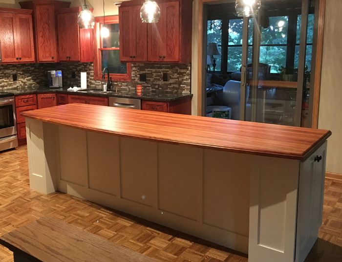 Foto på ett stort lantligt röd kök, med en undermonterad diskho, luckor med profilerade fronter, vita skåp, träbänkskiva, flerfärgad stänkskydd, stänkskydd i terrakottakakel, rostfria vitvaror, mellanmörkt trägolv, en köksö och brunt golv
