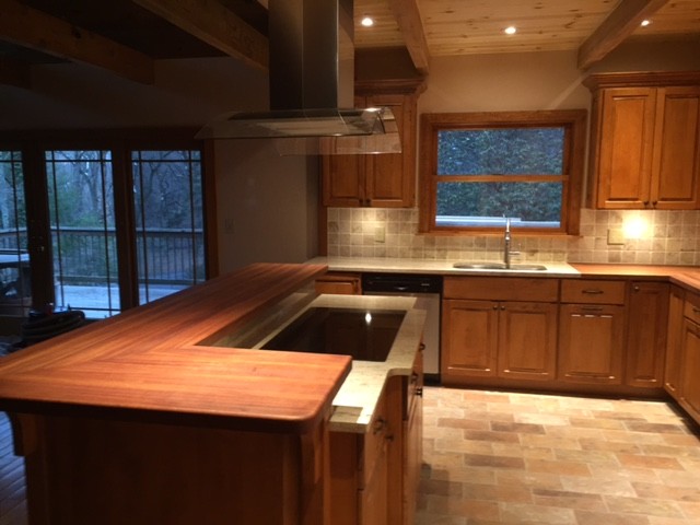 Exempel på ett mellanstort modernt röd rött kök, med en undermonterad diskho, luckor med upphöjd panel, skåp i mellenmörkt trä, träbänkskiva, beige stänkskydd, stänkskydd i keramik, rostfria vitvaror, klinkergolv i keramik, en köksö och brunt golv