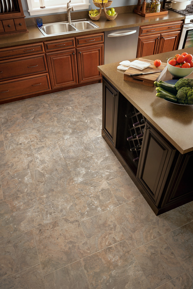 Photo of a medium sized traditional l-shaped kitchen in Other with a double-bowl sink, raised-panel cabinets, medium wood cabinets, composite countertops, stainless steel appliances, vinyl flooring, an island and grey floors.