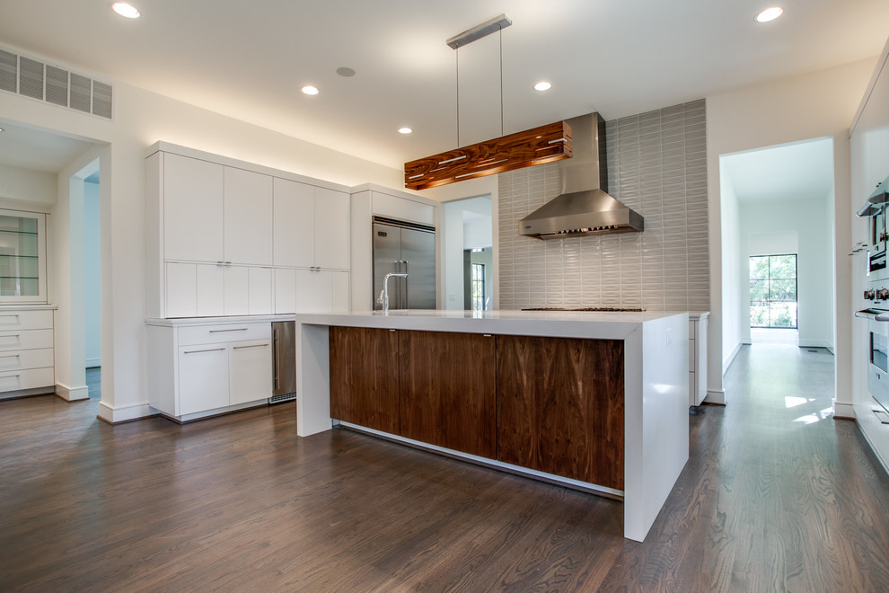 Example of a trendy enclosed kitchen design in Dallas with an undermount sink, flat-panel cabinets, white cabinets, gray backsplash and stainless steel appliances