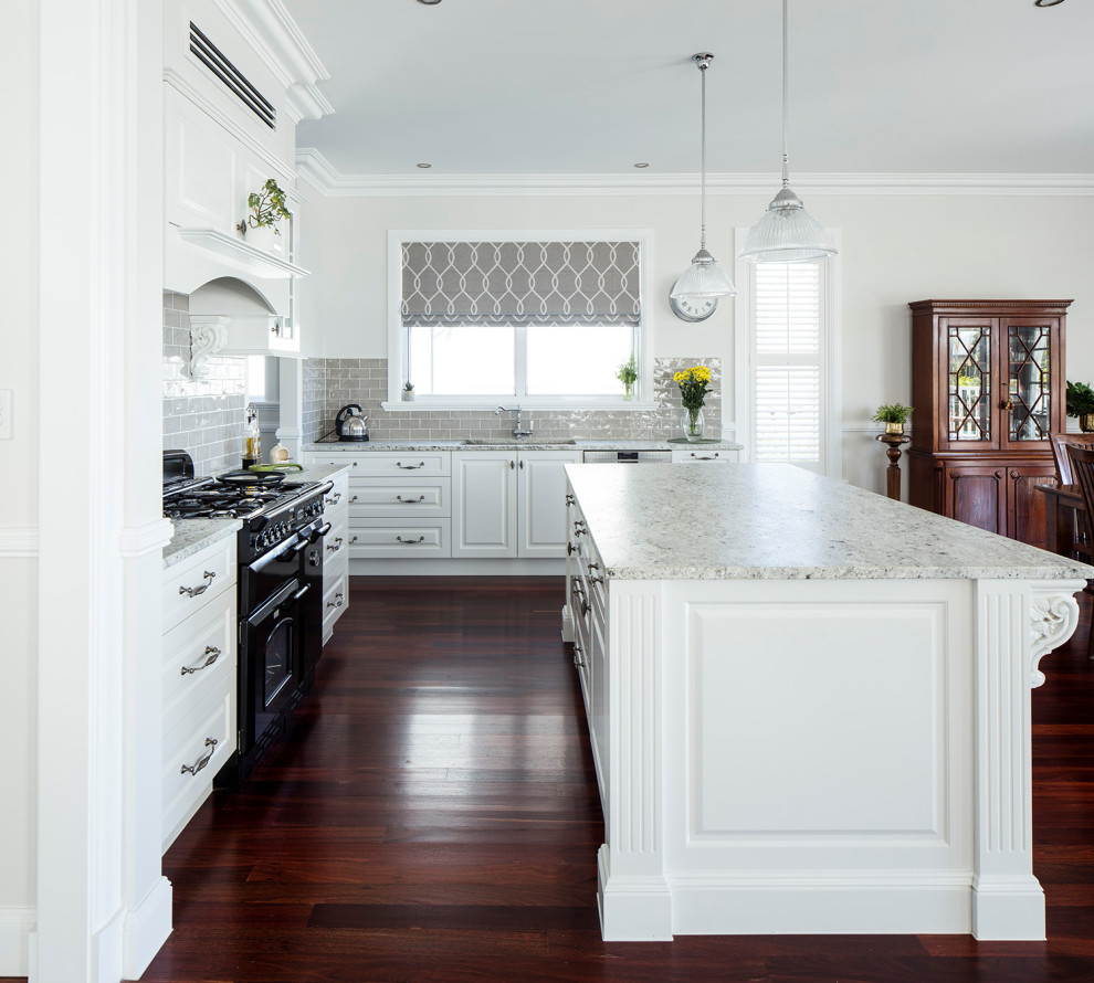 Bild på ett mellanstort vintage beige beige kök, med en undermonterad diskho, skåp i shakerstil, vita skåp, marmorbänkskiva, beige stänkskydd, stänkskydd i cementkakel, svarta vitvaror, mörkt trägolv, en köksö och rött golv