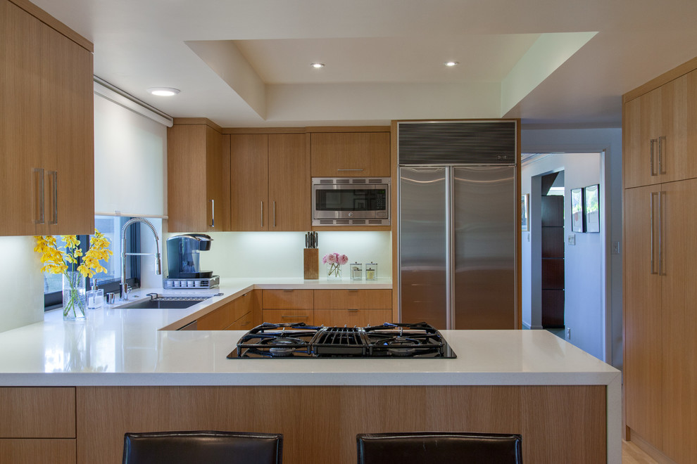 Moderne Küche in U-Form mit Unterbauwaschbecken, flächenbündigen Schrankfronten, hellbraunen Holzschränken, Küchengeräten aus Edelstahl und Halbinsel in Los Angeles