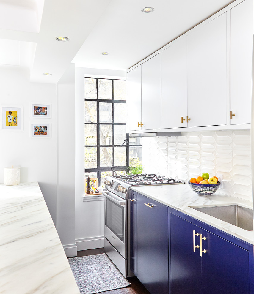 Small transitional galley dark wood floor and brown floor open concept kitchen photo in New York with an undermount sink, flat-panel cabinets, marble countertops, white backsplash, ceramic backsplash, stainless steel appliances, an island and blue cabinets