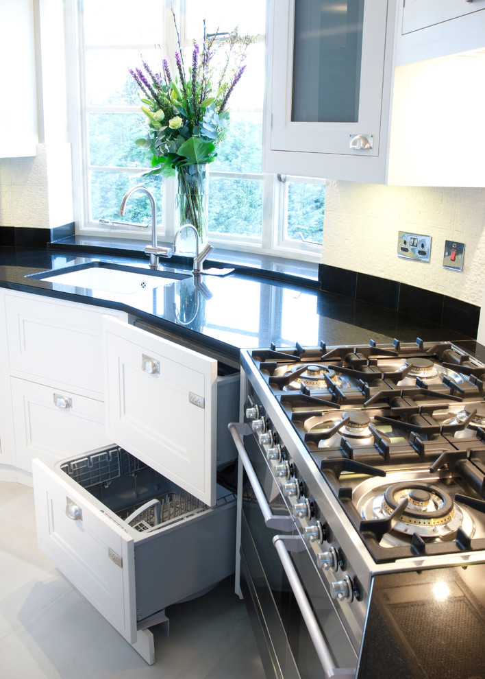 Immagine di una cucina classica chiusa e di medie dimensioni con lavello sottopiano, ante bianche, top in granito, paraspruzzi bianco e pavimento in pietra calcarea
