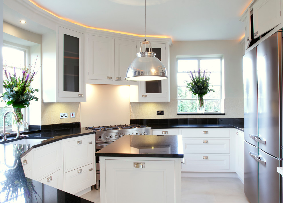 This is an example of a medium sized classic u-shaped enclosed kitchen in London with a submerged sink, white cabinets, granite worktops, white splashback, limestone flooring and an island.
