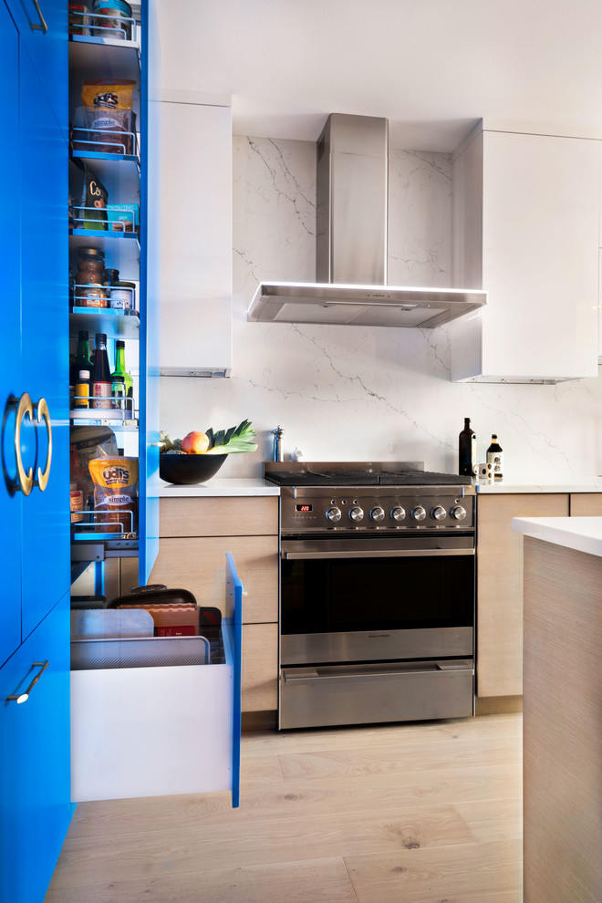 Foto di una cucina minimal di medie dimensioni con lavello integrato, ante lisce, ante blu, top in marmo, paraspruzzi bianco, paraspruzzi in marmo, elettrodomestici da incasso, parquet chiaro e top bianco