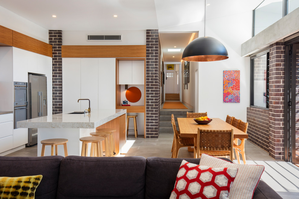 Offene Moderne Küche mit Unterbauwaschbecken, flächenbündigen Schrankfronten, weißen Schränken, Küchenrückwand in Weiß, Küchengeräten aus Edelstahl, Betonboden, Kücheninsel und grauem Boden in Sydney