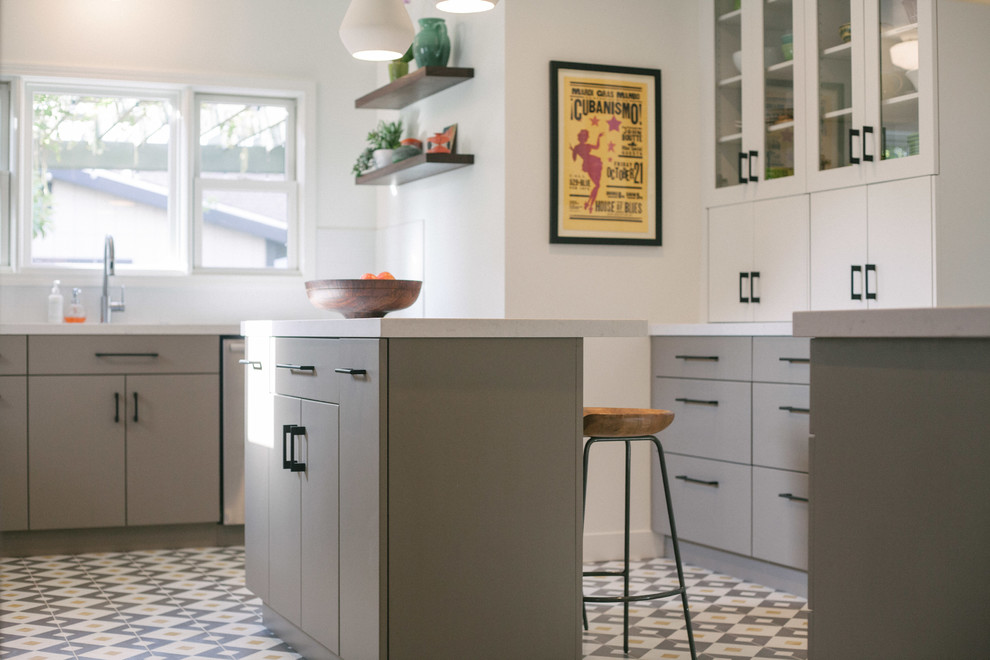 Example of a mid-sized trendy u-shaped cement tile floor and multicolored floor enclosed kitchen design in San Francisco with an undermount sink, flat-panel cabinets, brown cabinets, quartz countertops, white backsplash, ceramic backsplash, colored appliances and an island