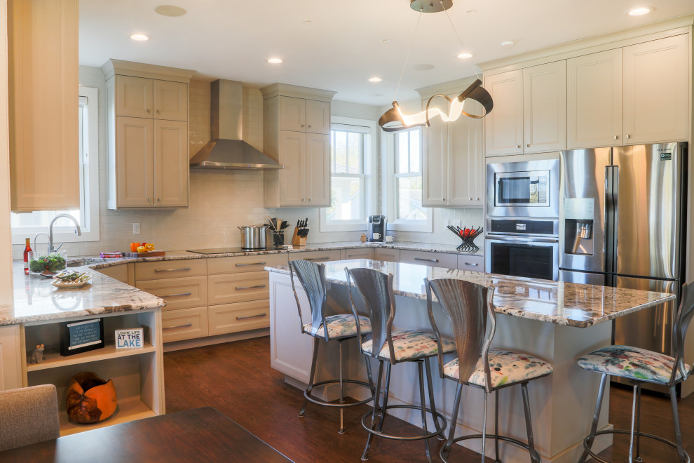 Exempel på ett stort modernt flerfärgad flerfärgat kök, med en undermonterad diskho, luckor med infälld panel, grå skåp, granitbänkskiva, vitt stänkskydd, stänkskydd i porslinskakel, rostfria vitvaror, mellanmörkt trägolv och en köksö