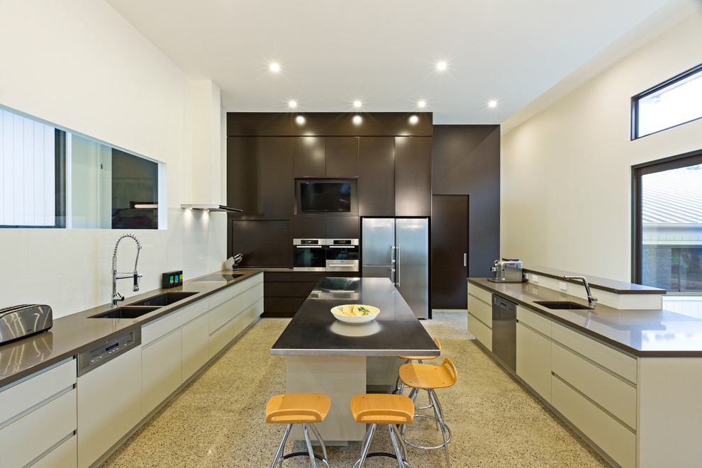 Esempio di una cucina design con lavello a doppia vasca, top in acciaio inossidabile, pavimento in cemento e 2 o più isole