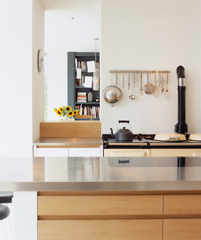 Esempio di una cucina design di medie dimensioni con ante lisce, ante bianche, top in acciaio inossidabile, paraspruzzi con lastra di vetro, lavello integrato, elettrodomestici in acciaio inossidabile e top grigio
