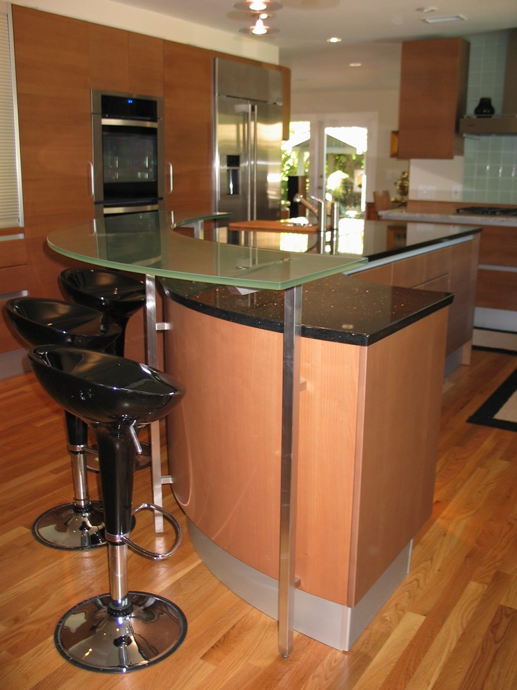 Modern inredning av ett mellanstort kök, med en dubbel diskho, släta luckor, skåp i mellenmörkt trä, bänkskiva i återvunnet glas, flerfärgad stänkskydd, stänkskydd i mosaik, integrerade vitvaror, mellanmörkt trägolv och en köksö