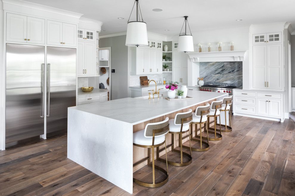 Kitchen - coastal l-shaped medium tone wood floor and brown floor kitchen idea in Minneapolis with a farmhouse sink, shaker cabinets, white cabinets, multicolored backsplash, stone slab backsplash, stainless steel appliances, an island and white countertops