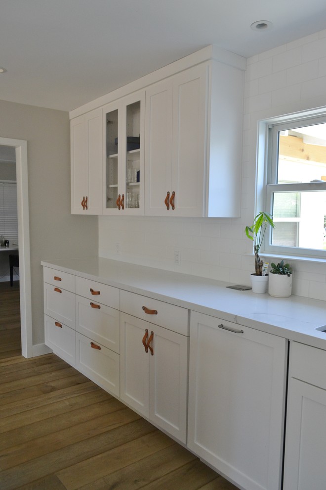 Idéer för att renovera ett stort lantligt vit vitt kök, med en undermonterad diskho, skåp i shakerstil, blå skåp, bänkskiva i kvarts, vitt stänkskydd, stänkskydd i tunnelbanekakel, rostfria vitvaror, ljust trägolv och brunt golv