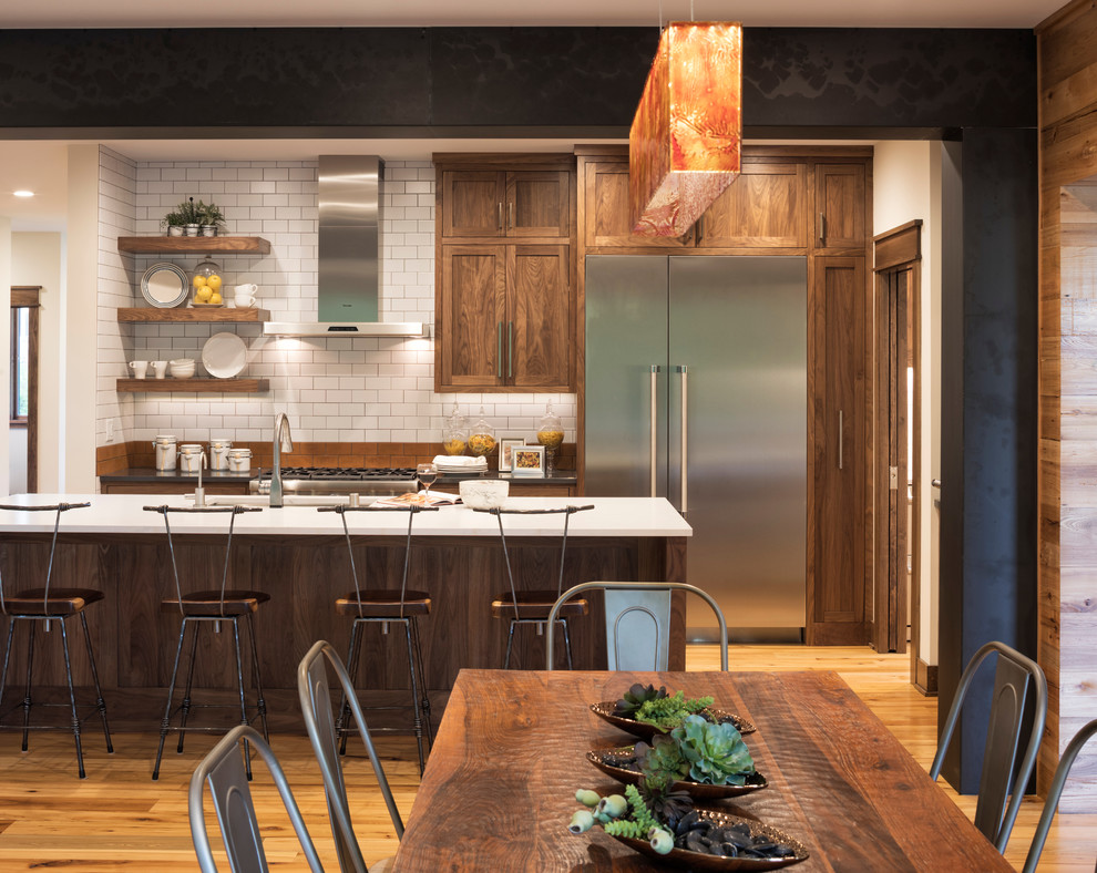 Rustik inredning av ett linjärt kök och matrum, med en undermonterad diskho, luckor med infälld panel, skåp i mörkt trä, vitt stänkskydd, rostfria vitvaror, mellanmörkt trägolv och en köksö