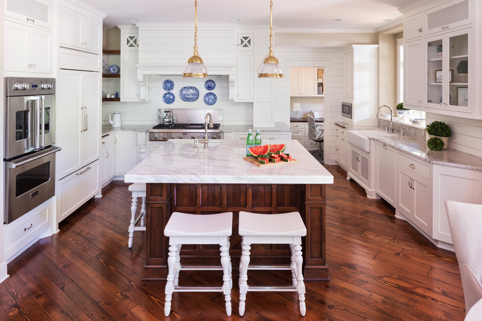 Example of a classic dark wood floor kitchen design in Minneapolis with a farmhouse sink, shaker cabinets, white cabinets, white backsplash, stainless steel appliances and an island