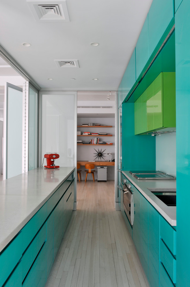 Photo of a modern galley kitchen in New York with stainless steel appliances, flat-panel cabinets and turquoise cabinets.