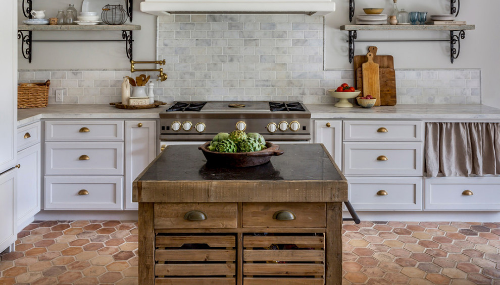 Example of a mid-sized transitional l-shaped terra-cotta tile and red floor enclosed kitchen design in San Francisco with recessed-panel cabinets, white cabinets, marble countertops, white backsplash, subway tile backsplash, stainless steel appliances, an island and white countertops