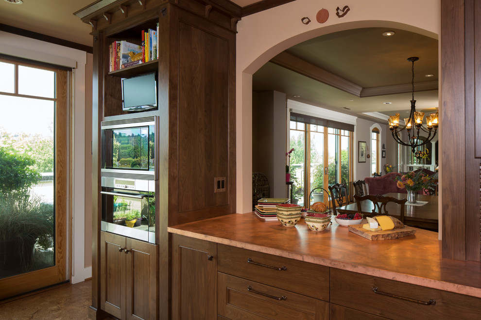 Exempel på ett avskilt klassiskt l-kök, med en undermonterad diskho, luckor med infälld panel, skåp i mellenmörkt trä, bänkskiva i akrylsten, grönt stänkskydd, stänkskydd i tunnelbanekakel och integrerade vitvaror