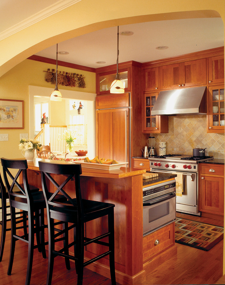 Ejemplo de cocina de estilo americano con encimera de granito, electrodomésticos con paneles, armarios estilo shaker, puertas de armario de madera oscura y salpicadero beige