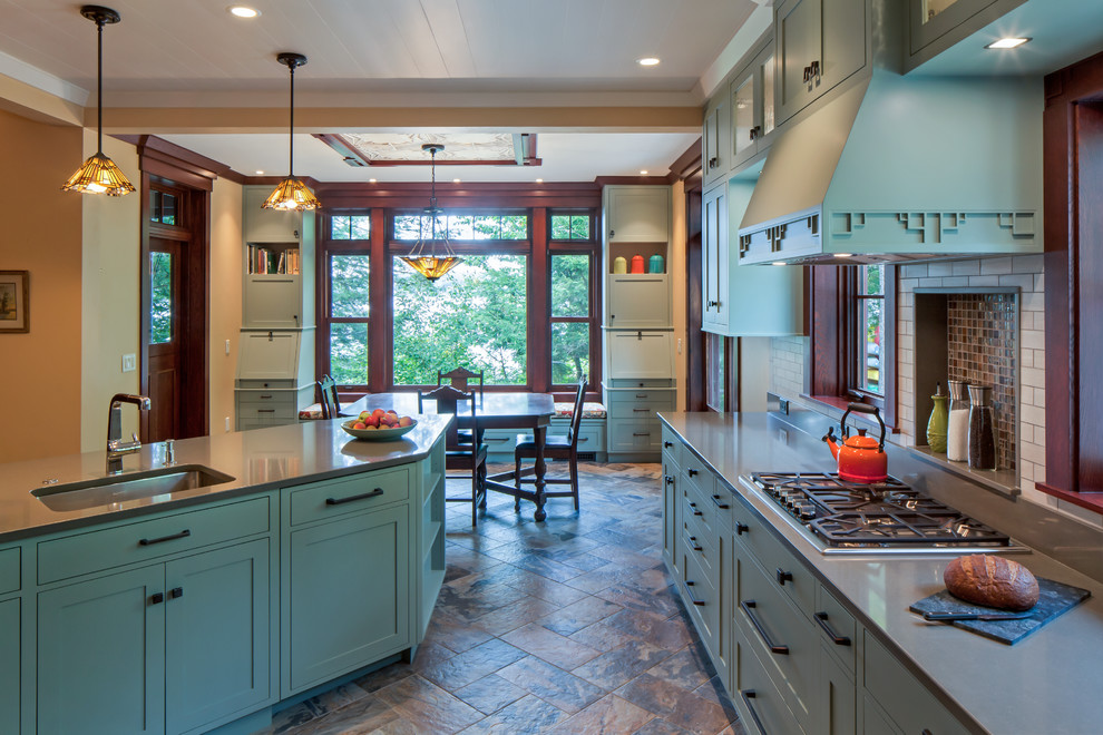 Example of a large arts and crafts single-wall multicolored floor eat-in kitchen design in Portland Maine with an undermount sink, shaker cabinets, green cabinets, quartz countertops, white backsplash, subway tile backsplash, stainless steel appliances, an island and gray countertops