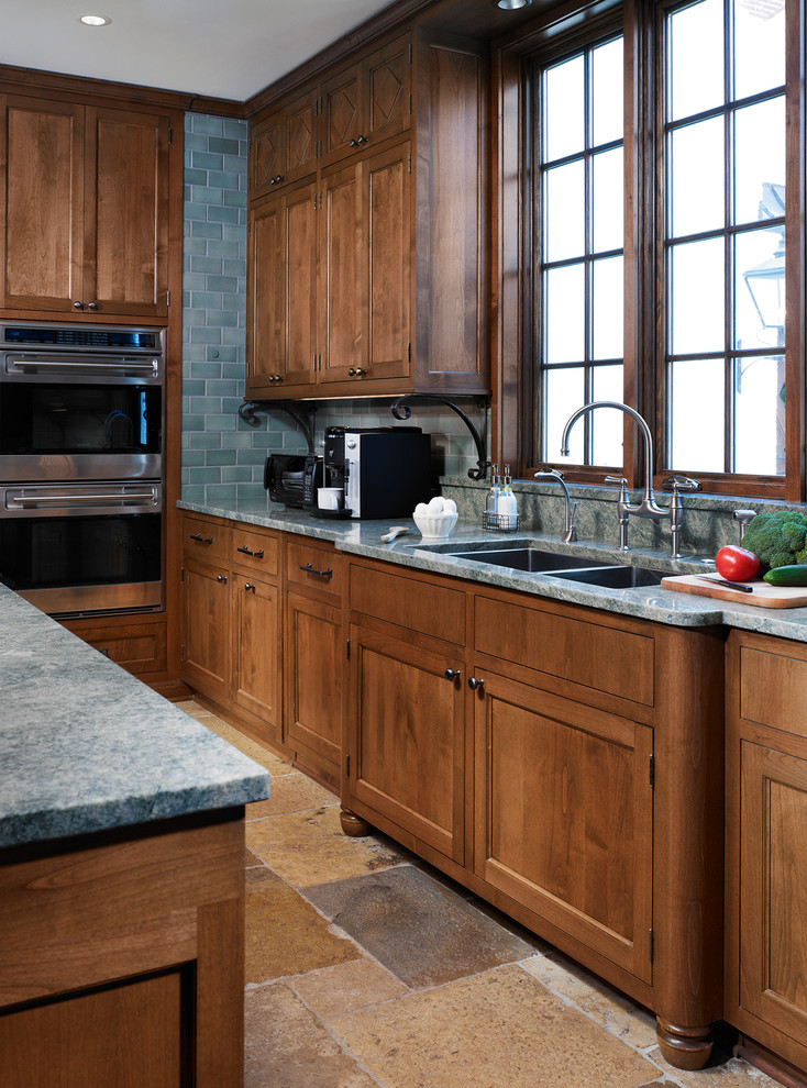 Example of a large classic u-shaped enclosed kitchen design in Chicago with an undermount sink, shaker cabinets, medium tone wood cabinets, quartzite countertops, green backsplash, stone tile backsplash, stainless steel appliances and an island