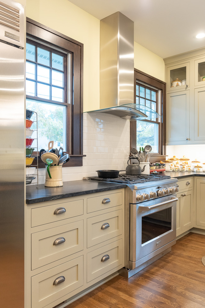 Inspiration for a craftsman medium tone wood floor and brown floor kitchen remodel in Indianapolis with gray cabinets, soapstone countertops, white backsplash, subway tile backsplash, stainless steel appliances and gray countertops