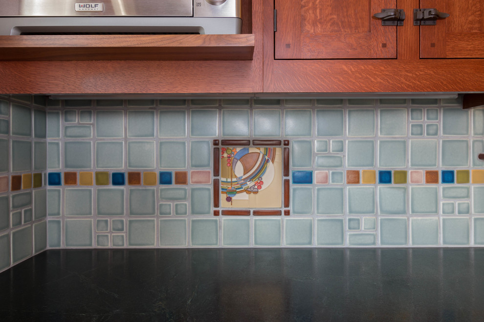 Small arts and crafts l-shaped light wood floor eat-in kitchen photo in Detroit with a farmhouse sink, beaded inset cabinets, brown cabinets, soapstone countertops, blue backsplash, mosaic tile backsplash, stainless steel appliances and no island