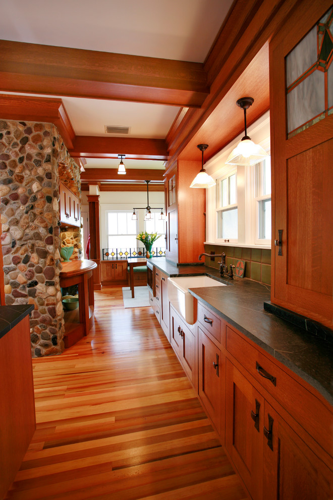 Amerikansk inredning av ett kök, med en rustik diskho, skåp i shakerstil, skåp i mellenmörkt trä, grönt stänkskydd och rostfria vitvaror