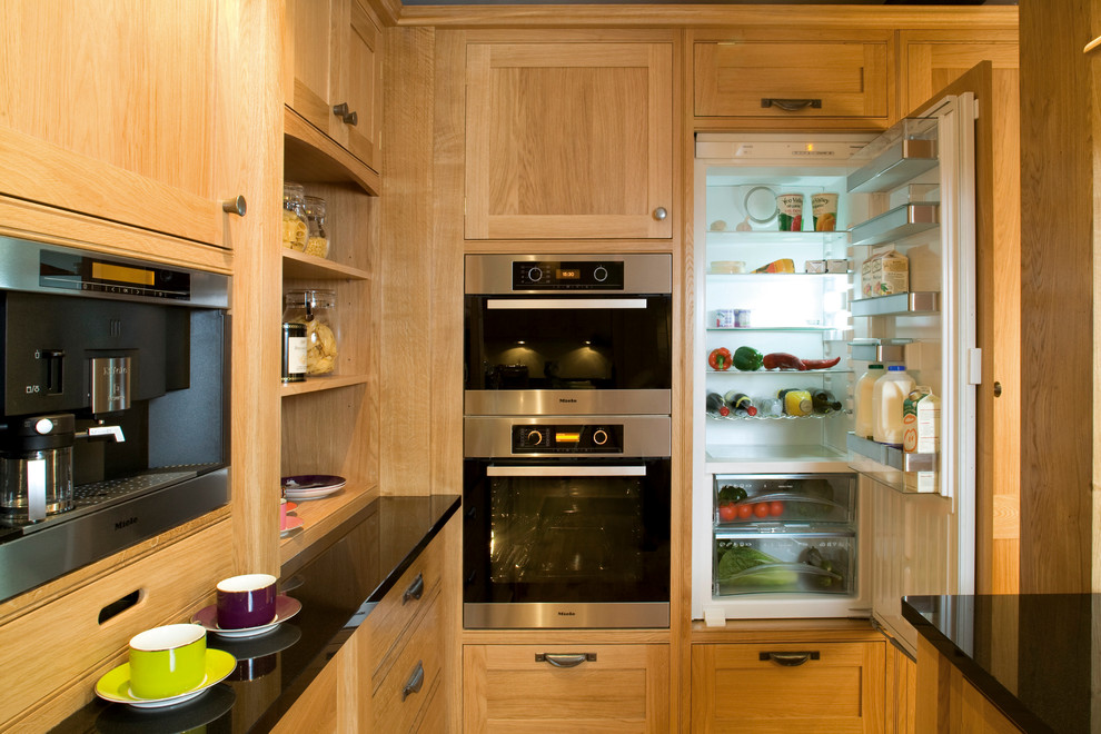Foto på ett mellanstort amerikanskt kök, med skåp i mellenmörkt trä, granitbänkskiva, beige stänkskydd, stänkskydd i keramik, rostfria vitvaror, mellanmörkt trägolv och en köksö