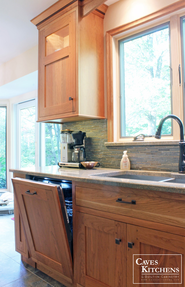 Inredning av ett amerikanskt mellanstort kök, med en undermonterad diskho, luckor med infälld panel, skåp i mellenmörkt trä, bänkskiva i kvarts, flerfärgad stänkskydd, stänkskydd i stickkakel, rostfria vitvaror, klinkergolv i terrakotta och en köksö