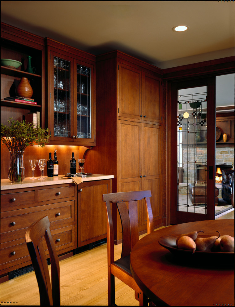 Example of a large classic l-shaped light wood floor enclosed kitchen design in Chicago with a single-bowl sink, flat-panel cabinets, dark wood cabinets, limestone countertops, beige backsplash, ceramic backsplash, paneled appliances and an island