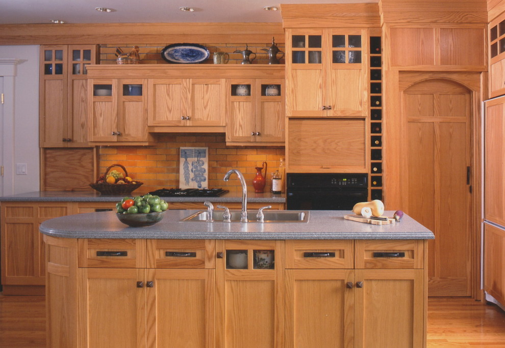 Пример оригинального дизайна: угловая кухня в стиле кантри с обеденным столом, накладной мойкой, фасадами в стиле шейкер, темными деревянными фасадами, столешницей из акрилового камня, оранжевым фартуком и черной техникой
