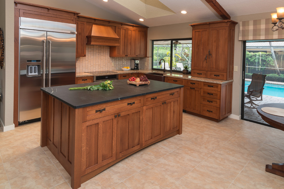 Eat-in kitchen - large craftsman beige floor eat-in kitchen idea in Miami with a farmhouse sink, shaker cabinets, brown cabinets, soapstone countertops, white backsplash, ceramic backsplash, stainless steel appliances and an island