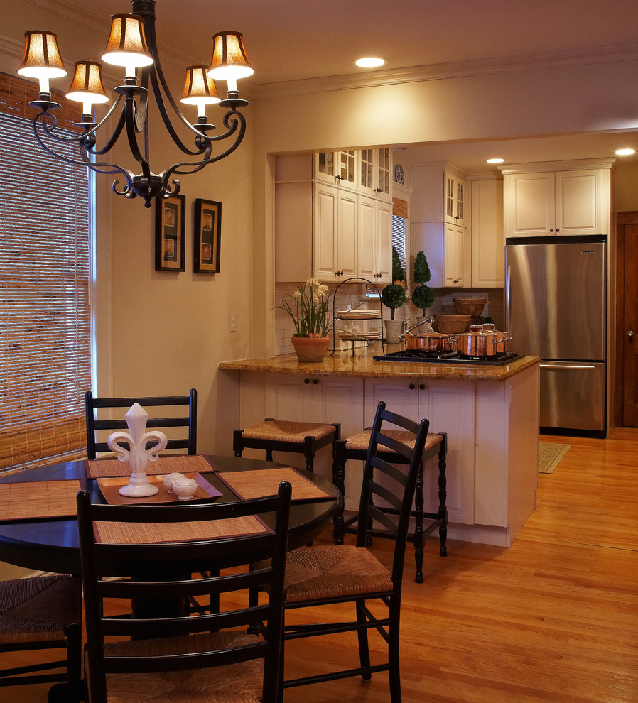Bild på ett litet eklektiskt kök, med en undermonterad diskho, luckor med upphöjd panel, vita skåp, granitbänkskiva, vitt stänkskydd, stänkskydd i keramik, rostfria vitvaror, mellanmörkt trägolv och en köksö