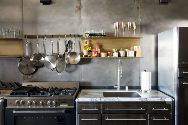Idéer för små industriella linjära kök och matrum, med en undermonterad diskho, skåp i rostfritt stål, marmorbänkskiva, grått stänkskydd, rostfria vitvaror och betonggolv