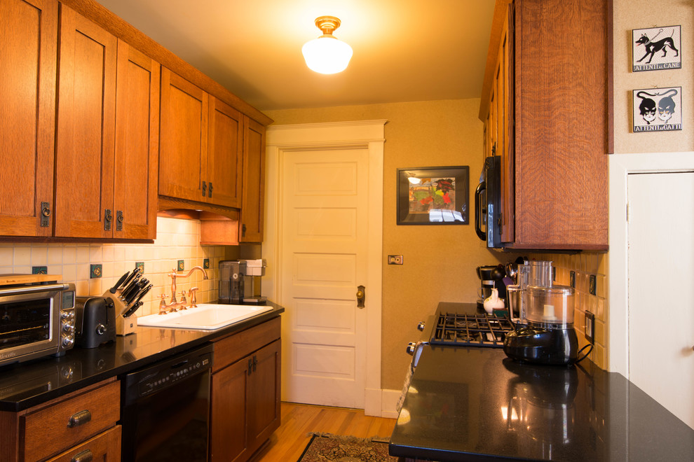 Enclosed kitchen - small craftsman galley medium tone wood floor enclosed kitchen idea in New York with a single-bowl sink, recessed-panel cabinets, dark wood cabinets, quartz countertops, yellow backsplash, ceramic backsplash, stainless steel appliances and no island