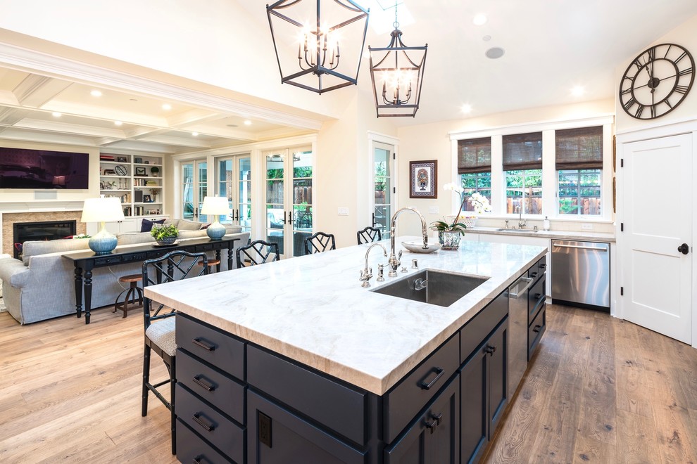 Photo of a large classic kitchen in San Francisco with a submerged sink, shaker cabinets, white cabinets, quartz worktops, beige splashback, metro tiled splashback, stainless steel appliances, light hardwood flooring and an island.