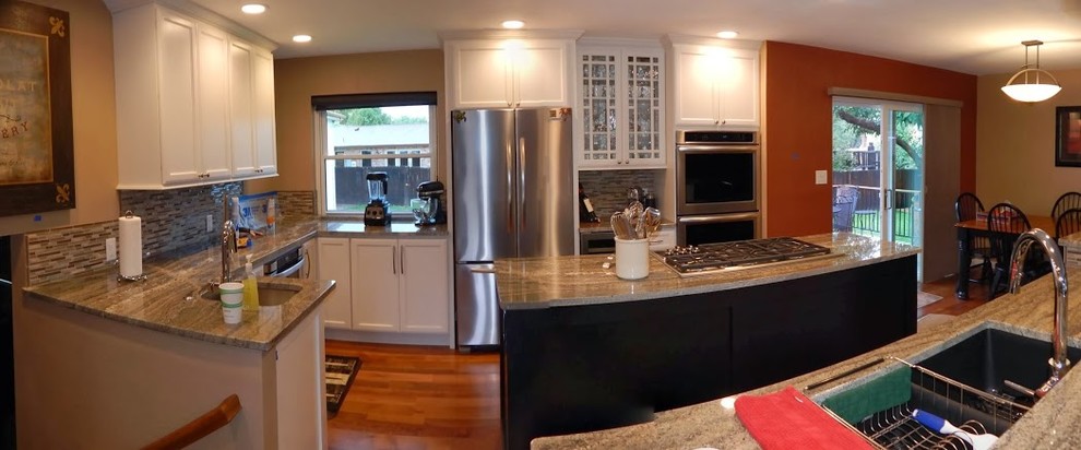 Exempel på ett stort modernt kök, med skåp i shakerstil, vita skåp, flera köksöar, en dubbel diskho, granitbänkskiva, flerfärgad stänkskydd, glaspanel som stänkskydd, rostfria vitvaror och mörkt trägolv