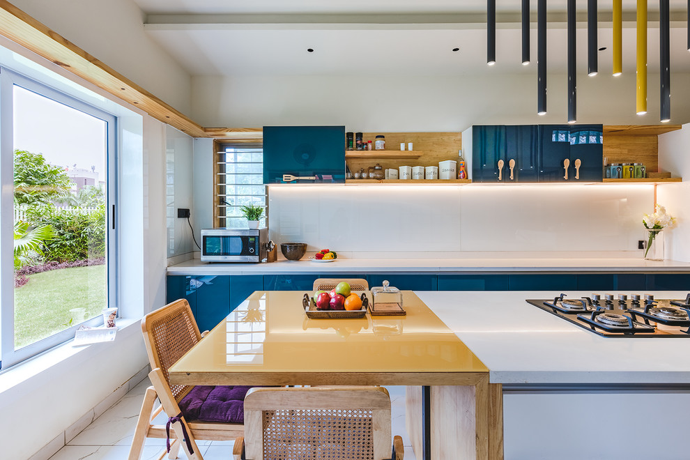 На фото: параллельная кухня в восточном стиле с обеденным столом, плоскими фасадами, синими фасадами, белым фартуком, фартуком из стекла, белым полом и желтой столешницей