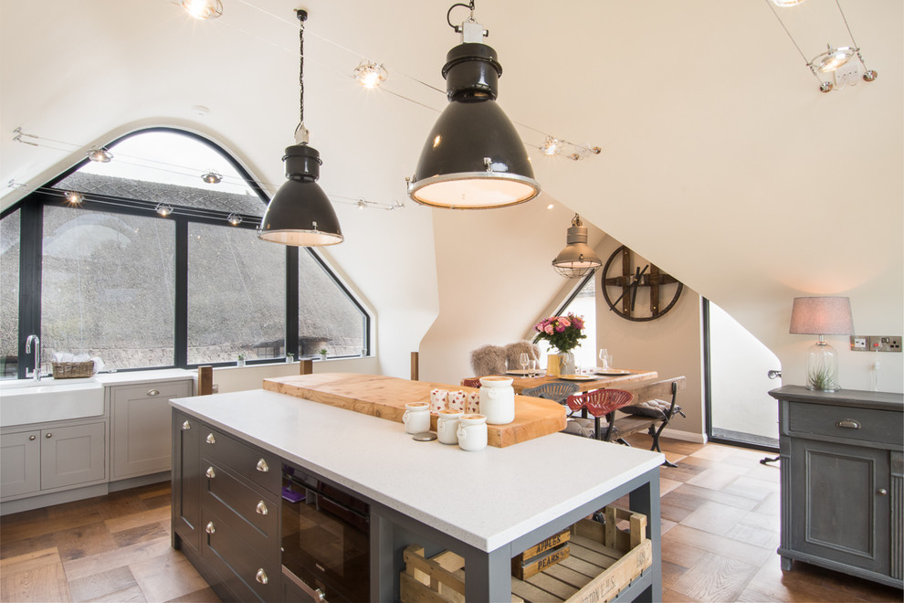 Foto di una cucina scandinava di medie dimensioni con lavello stile country, ante in stile shaker, ante grigie, elettrodomestici da incasso, pavimento in legno massello medio e pavimento marrone